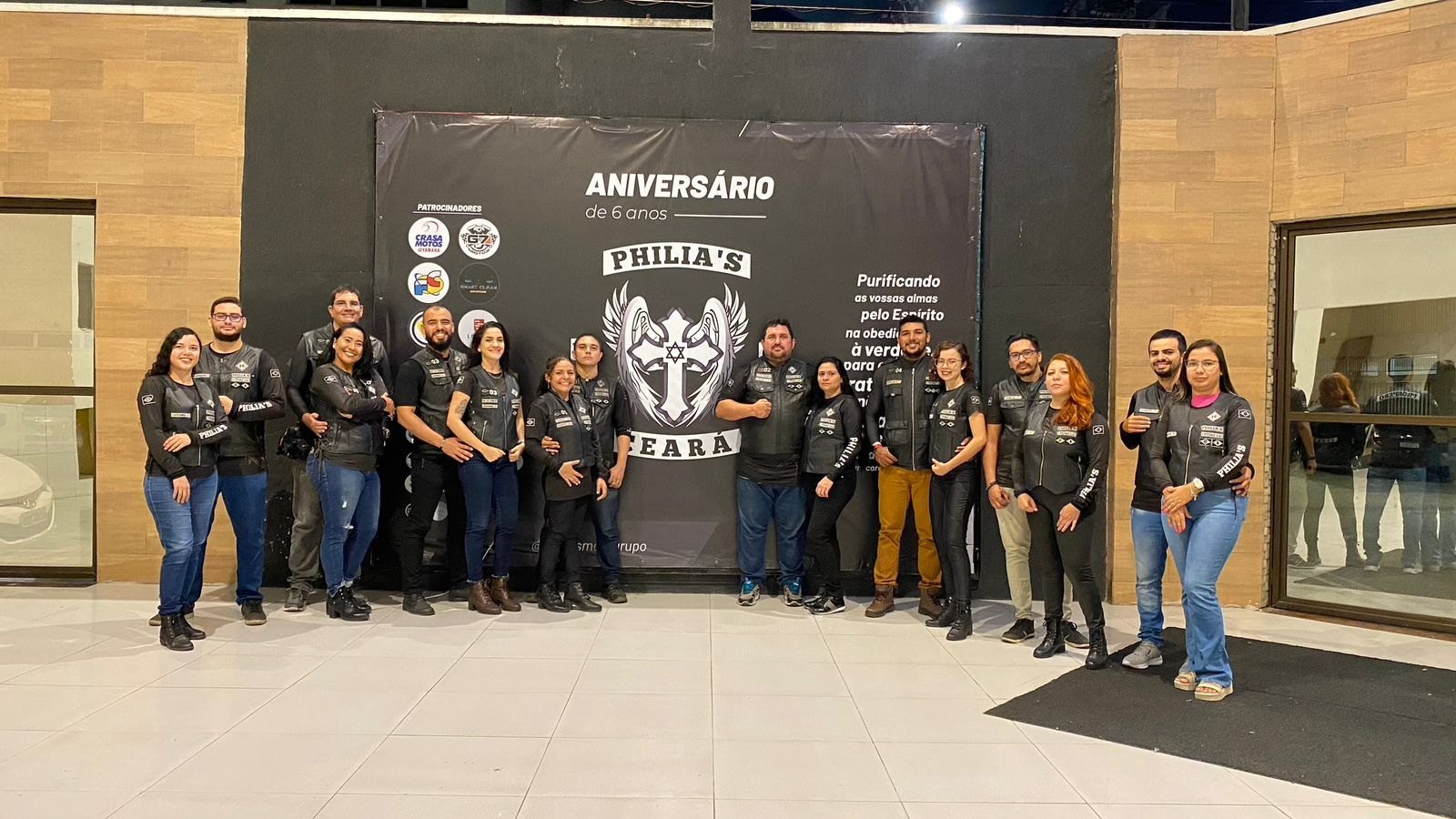 Membros do Philia's MG Ceará em frente ao painel do aniversário do grupo